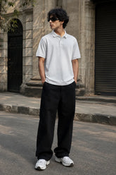 Model wearing the RENQARA White Polo T-Shirt crafted from premium 230 GSM piqué cotton with relaxed black trousers.