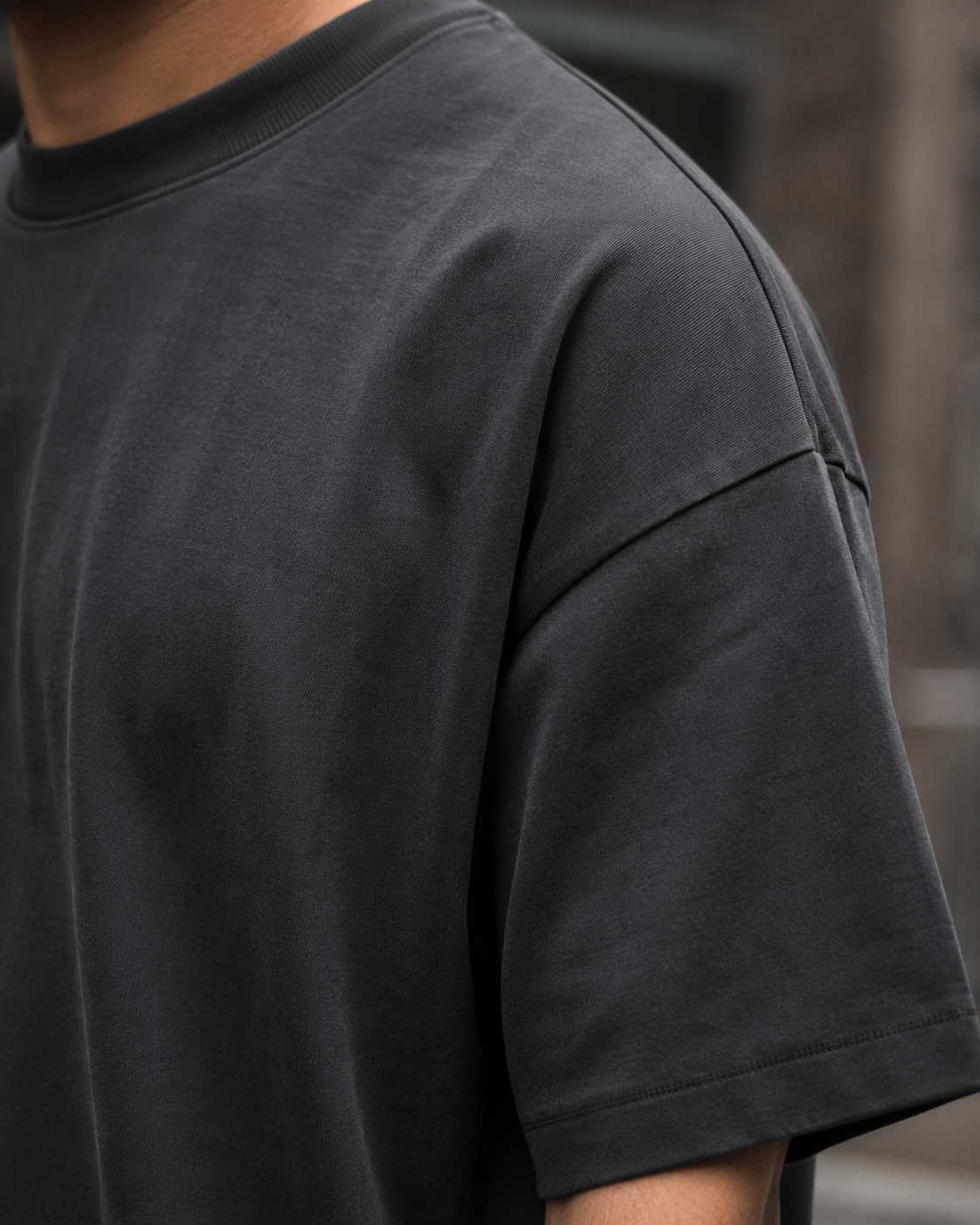 Close-up fabric detail of the RENQARA Onyx oversized t-shirt, showing the shoulder seam, sleeve construction, and smooth cotton texture.