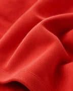 RENQARA Brick Red Oversized T-Shirt macro close-up showing cotton knit texture, fabric folds and stitching detail