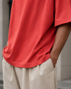 RENQARA Brick Red Oversized T-Shirt close-up showing hem stitching, side drape and cotton fabric fall