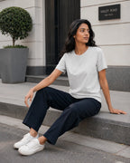 RENQARA Melange Grey Women’s Regular Fit T-Shirt seated lifestyle look styled with navy trousers and white sneakers